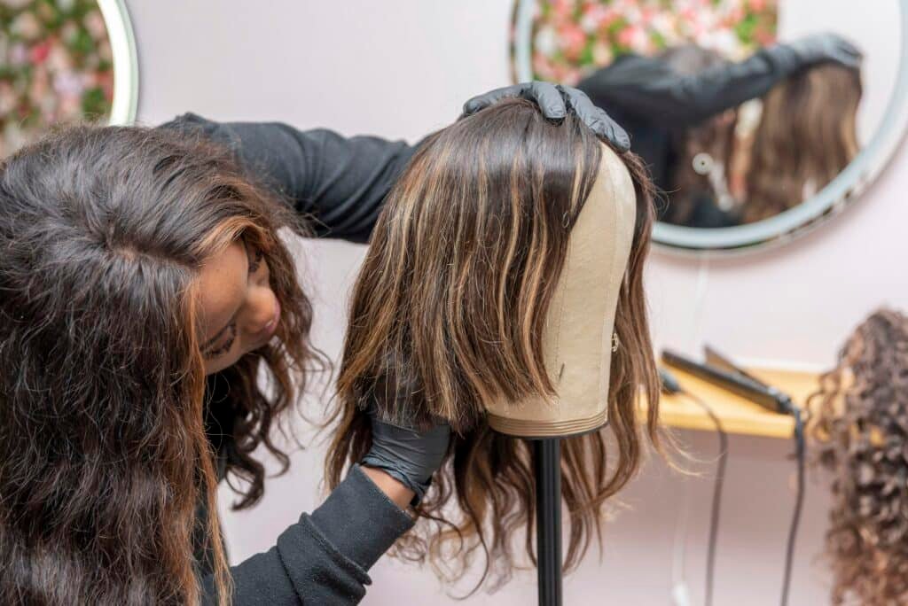 How to Style Your U Part Wig Like a Pro a young hairdressing student working the wig on mannequin's head