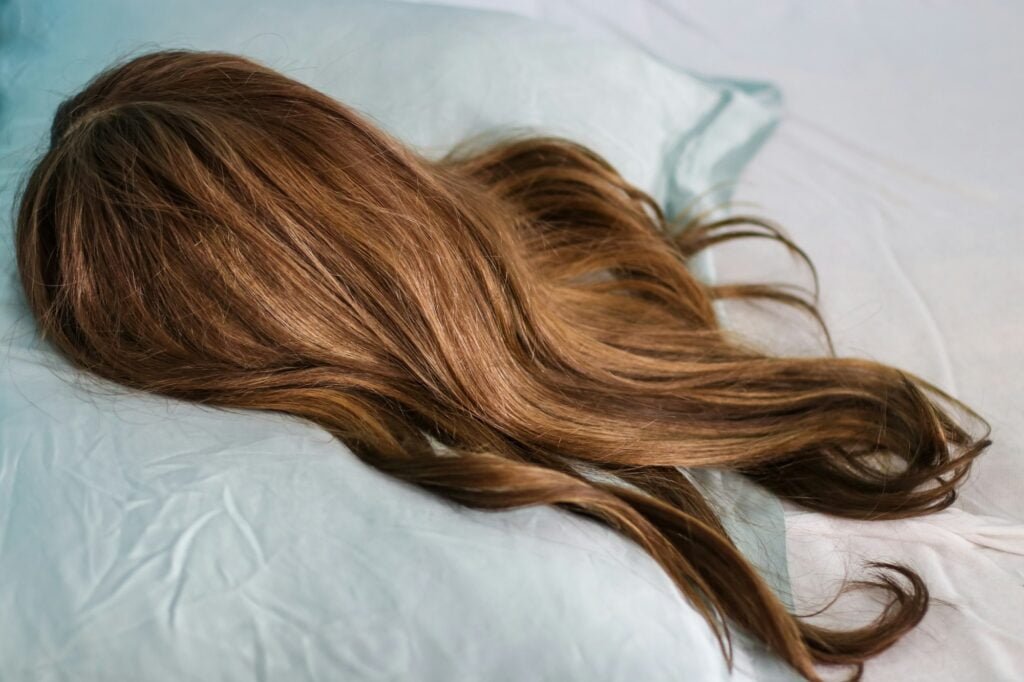 Blonde Wig in Style Closeup of a brunette wig with highlights on a silk pillow