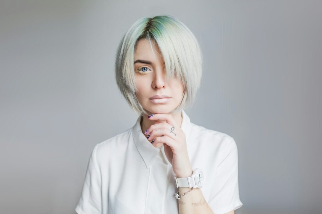 Effortlessly Stylish: Blonde Wig with Bangs Ideas Portrait of pretty girl with gray short hairstyle on gray background. She wears white dress and