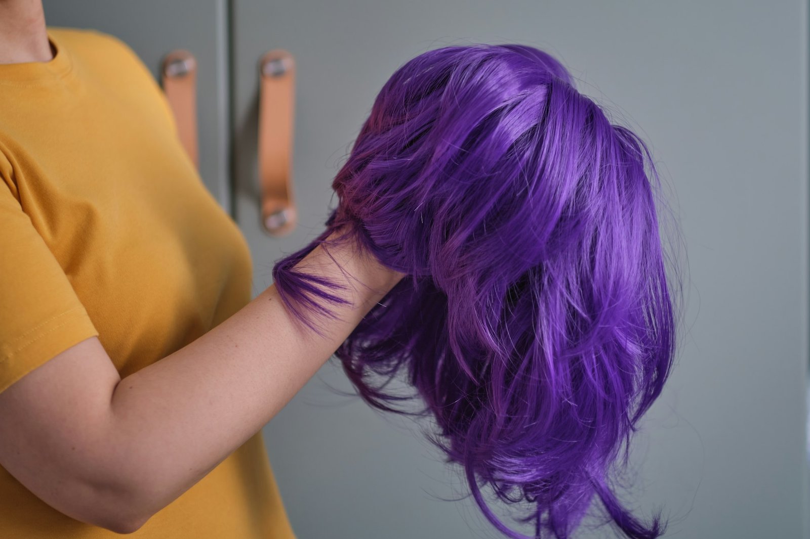 Slay with Elegance: Purple Wig Tips + Special Code woman holds a bright purple wig in her hands. Womens beauty concept