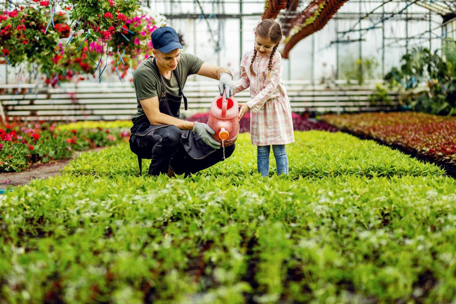 Top 10 Blue Flowers to Plant This Spring Young worker and small girl watering flowers at plant nursery.